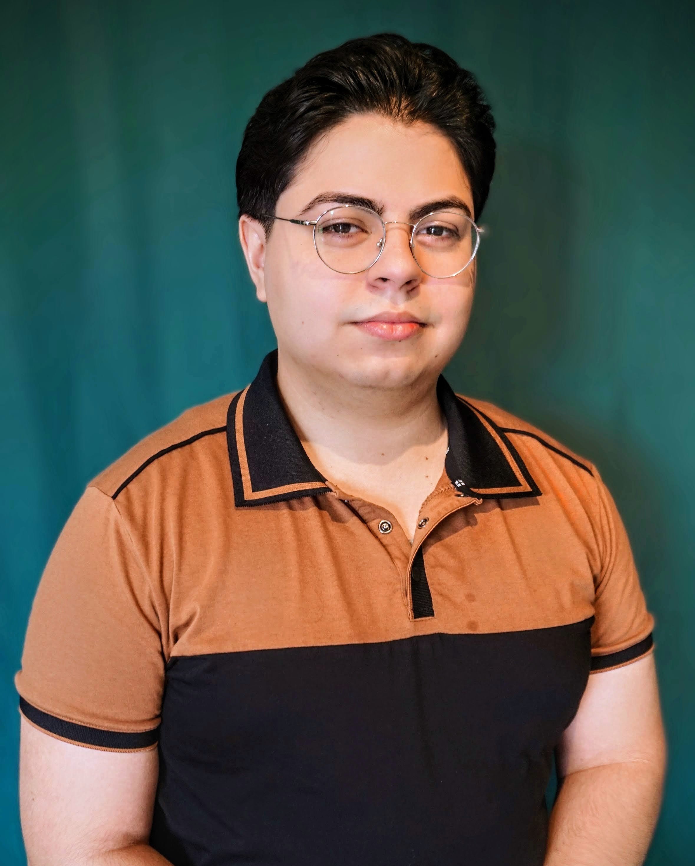 Headshot of smiling male tutor with medium-length black hair wearing a lanyard.