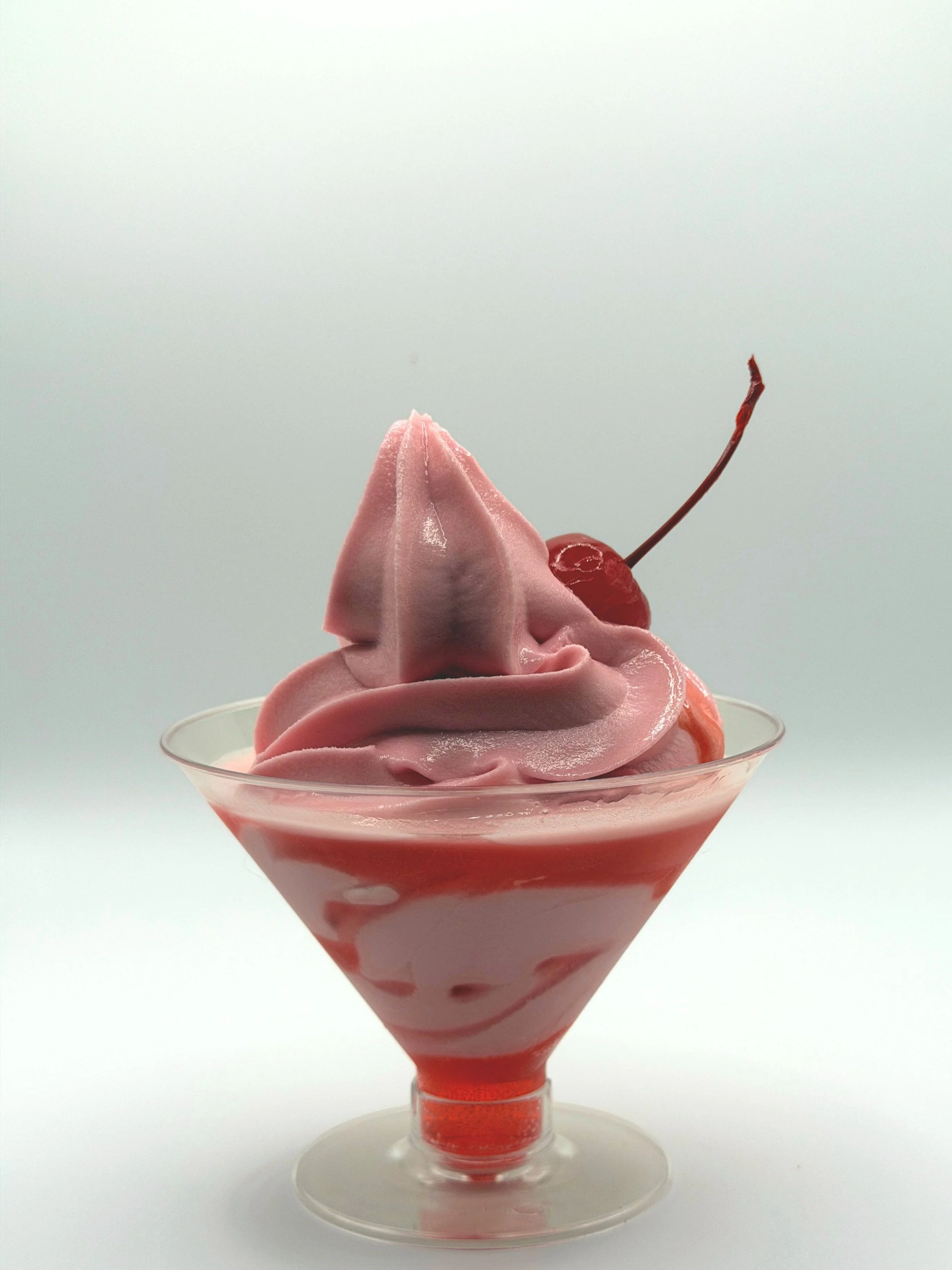 Cherry soft-serve cocktail in a martini glass with a grenadine drizzle and a cherry garnish.