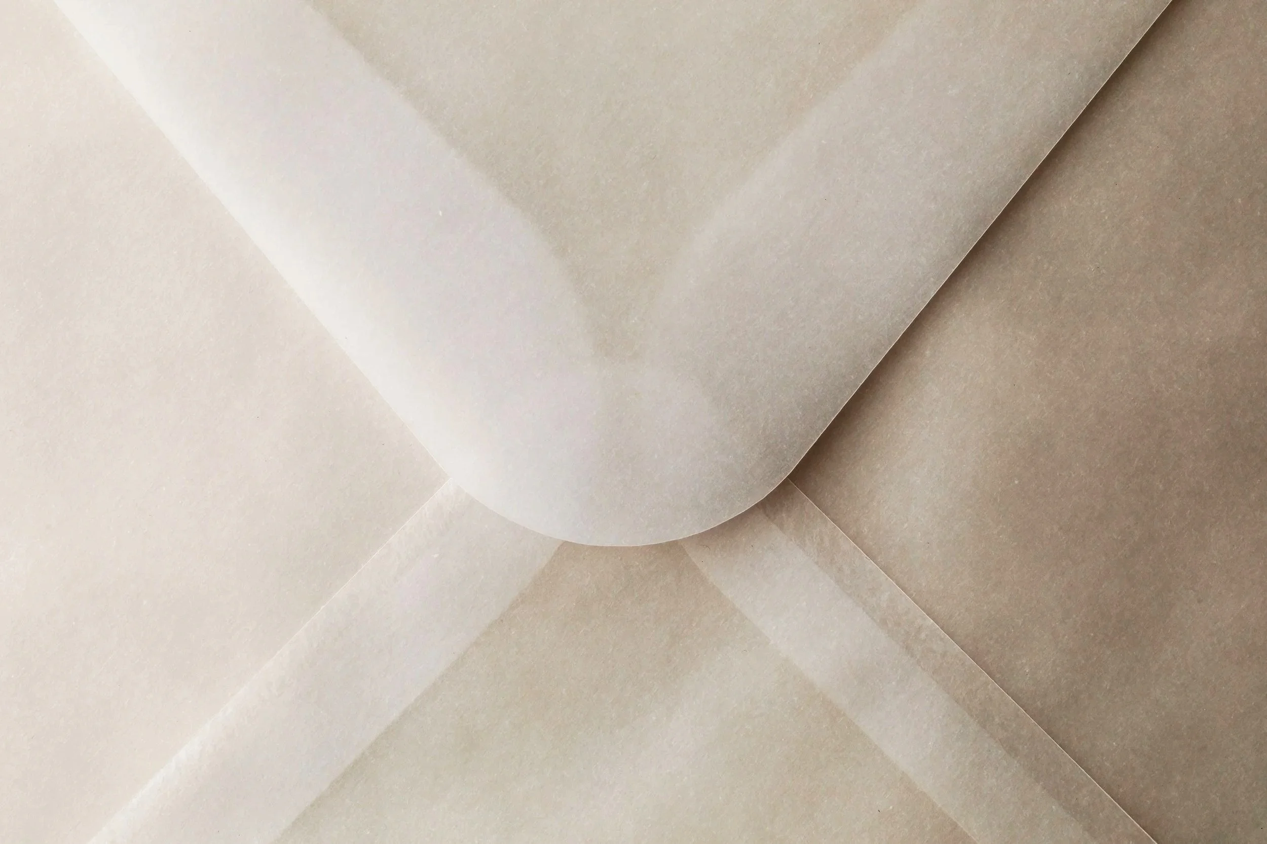 Close-up of layered beige paper sheets with one folded over edge.