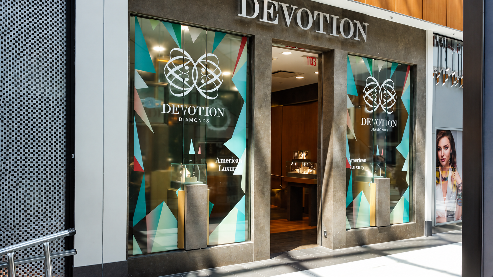 Storefront of Devotion Diamonds jewelry store with glass windows displaying the logo and an advertisement with a woman wearing jewelry.