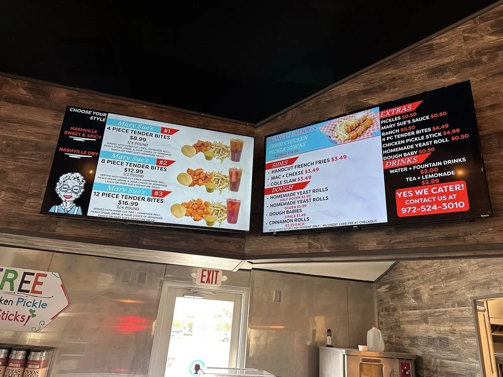 Digital menu board with food and side options, drinks, extras, and contact information at a restaurant. The menu features pieces tender bites, sides like French fries and rolls, and drinks including fountain water and tea.