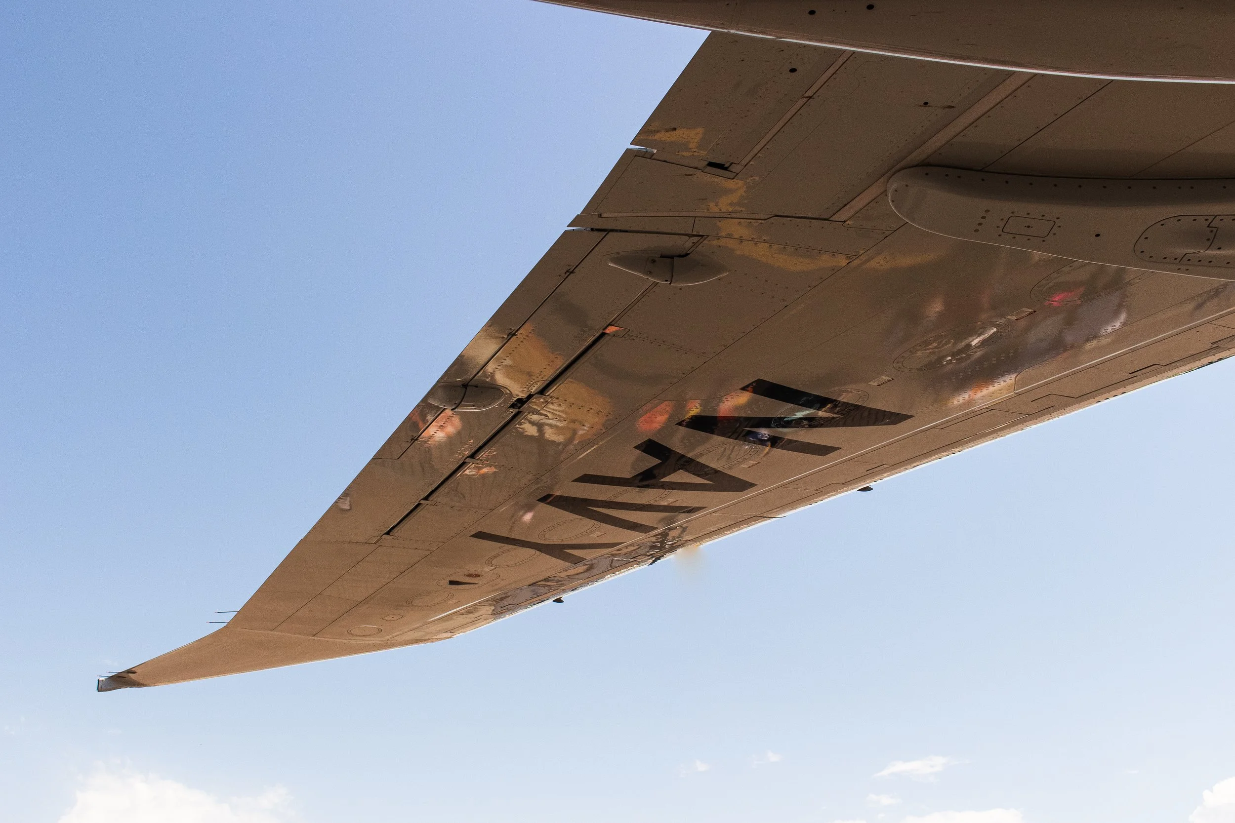 Close-up of the underside of an airplane wing with a clear blue sky in the background.