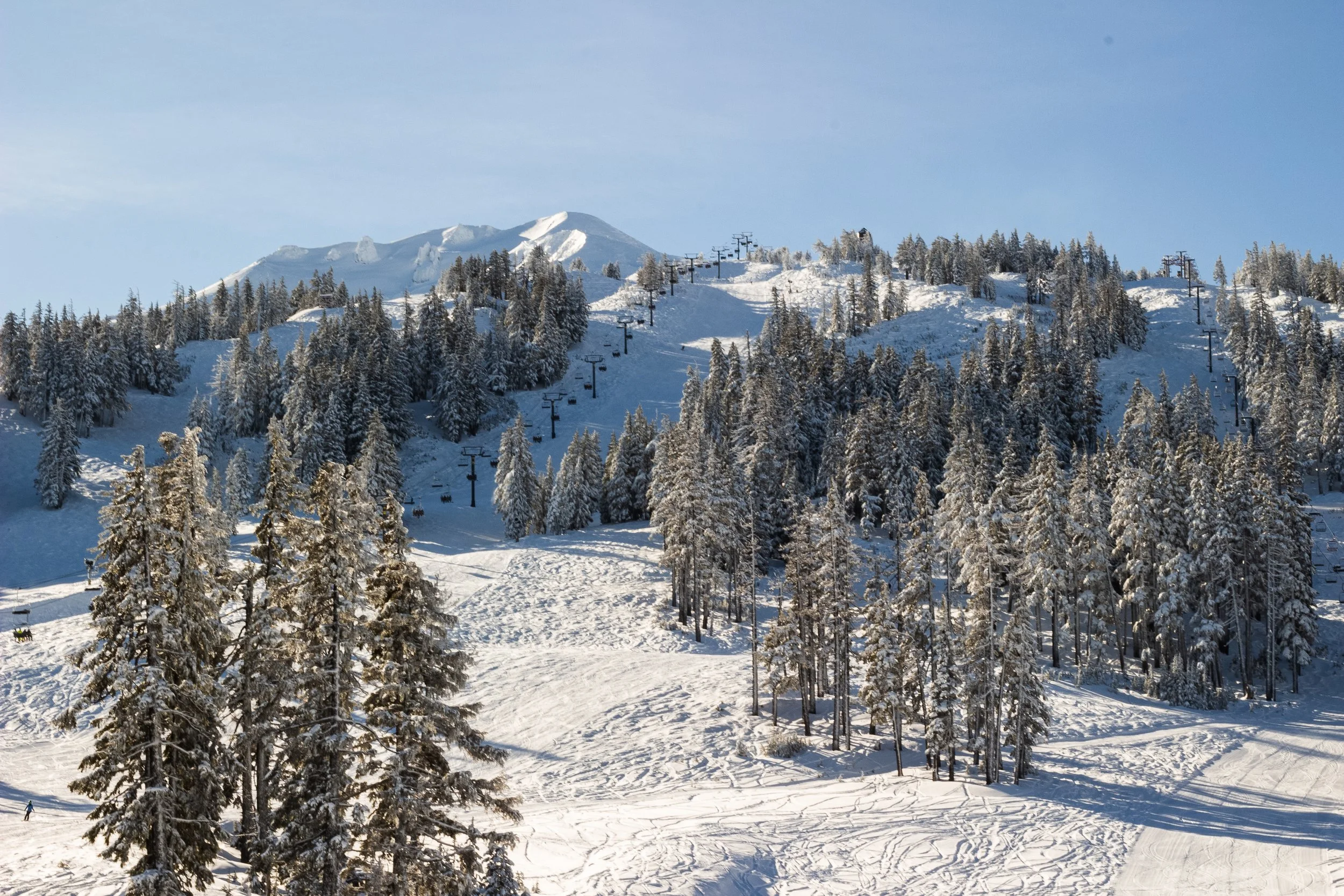 Snow-covered mountain with ski lift chairs and trees in winter.