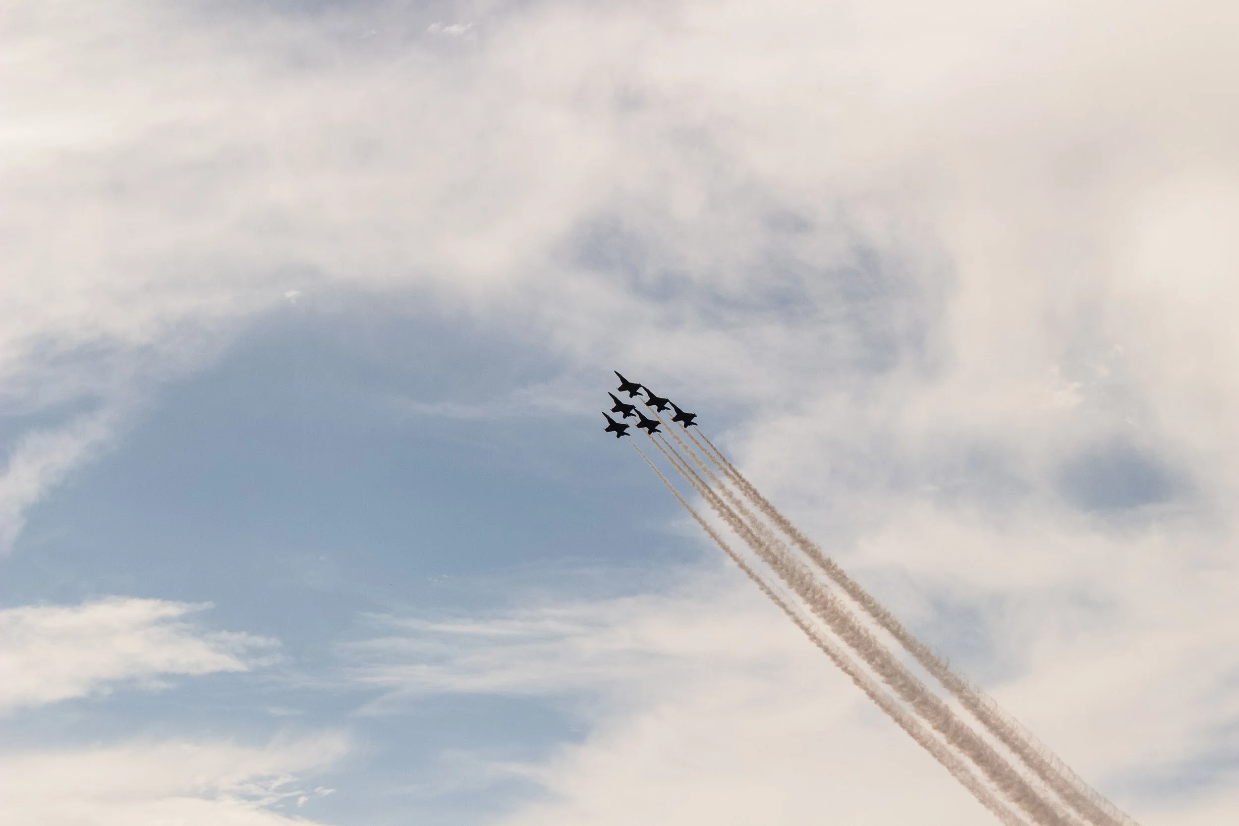 Six fighter jets flying in formation with smoke trails in the sky during an air show.