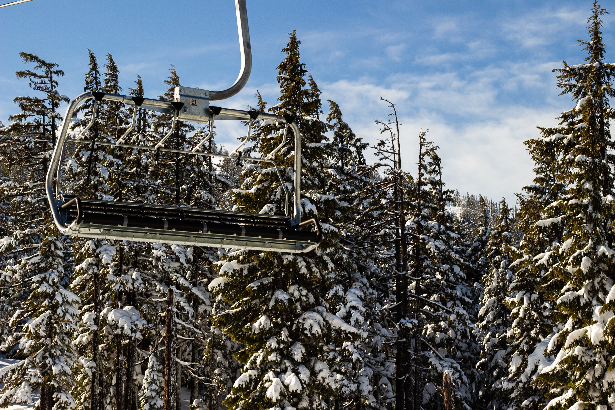 Snow-covered trees with a ski lift in the foreground on a clear winter day.