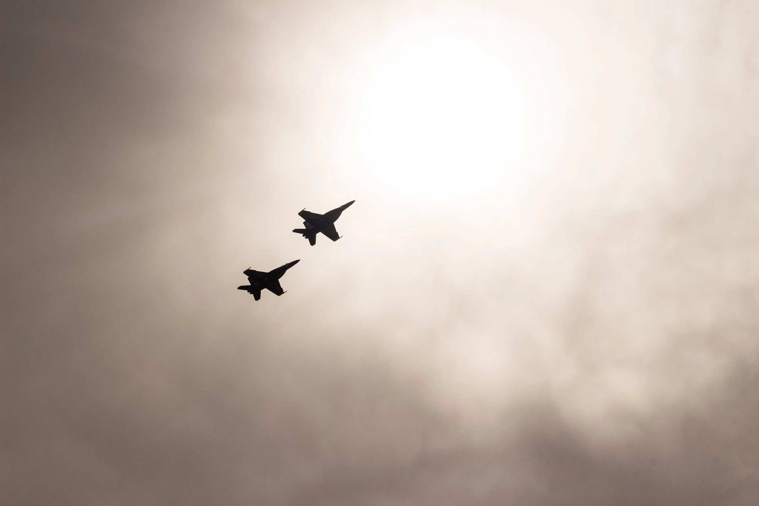 Three fighter jets flying in formation against a cloudy sky.