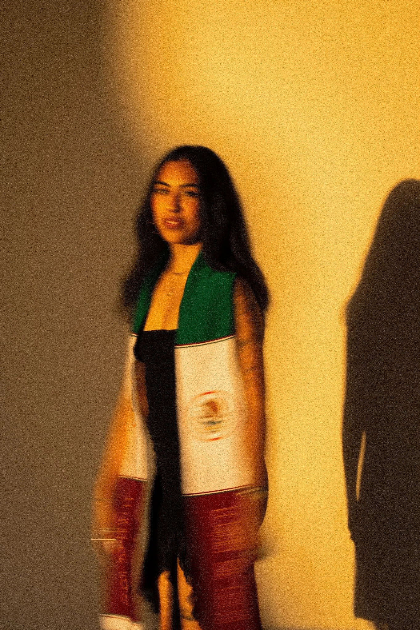 Magaly in her graduation stole against a warm sunlit wall