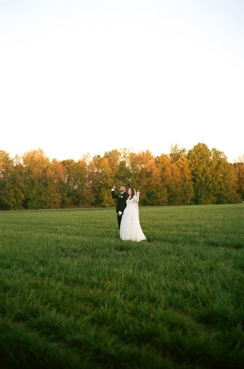 Carley and Preston standing far out in a wide green field, shot on film