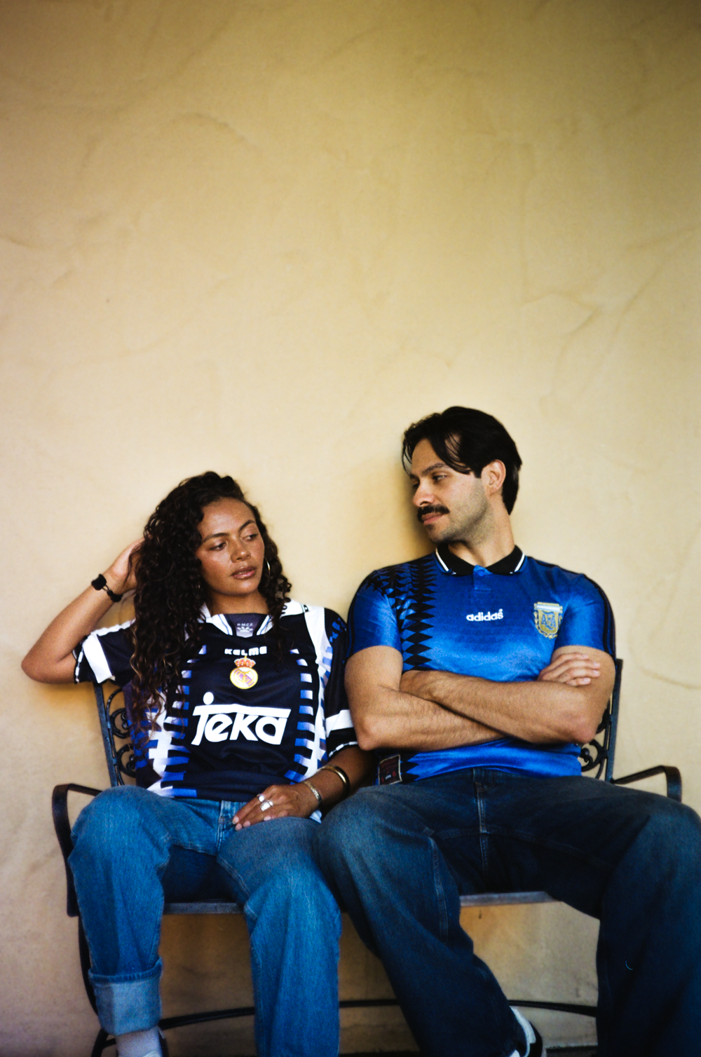 Jackie and Albert sitting against a warm wall in vintage Retro Locker kits at Balboa Park, shot on 35mm film