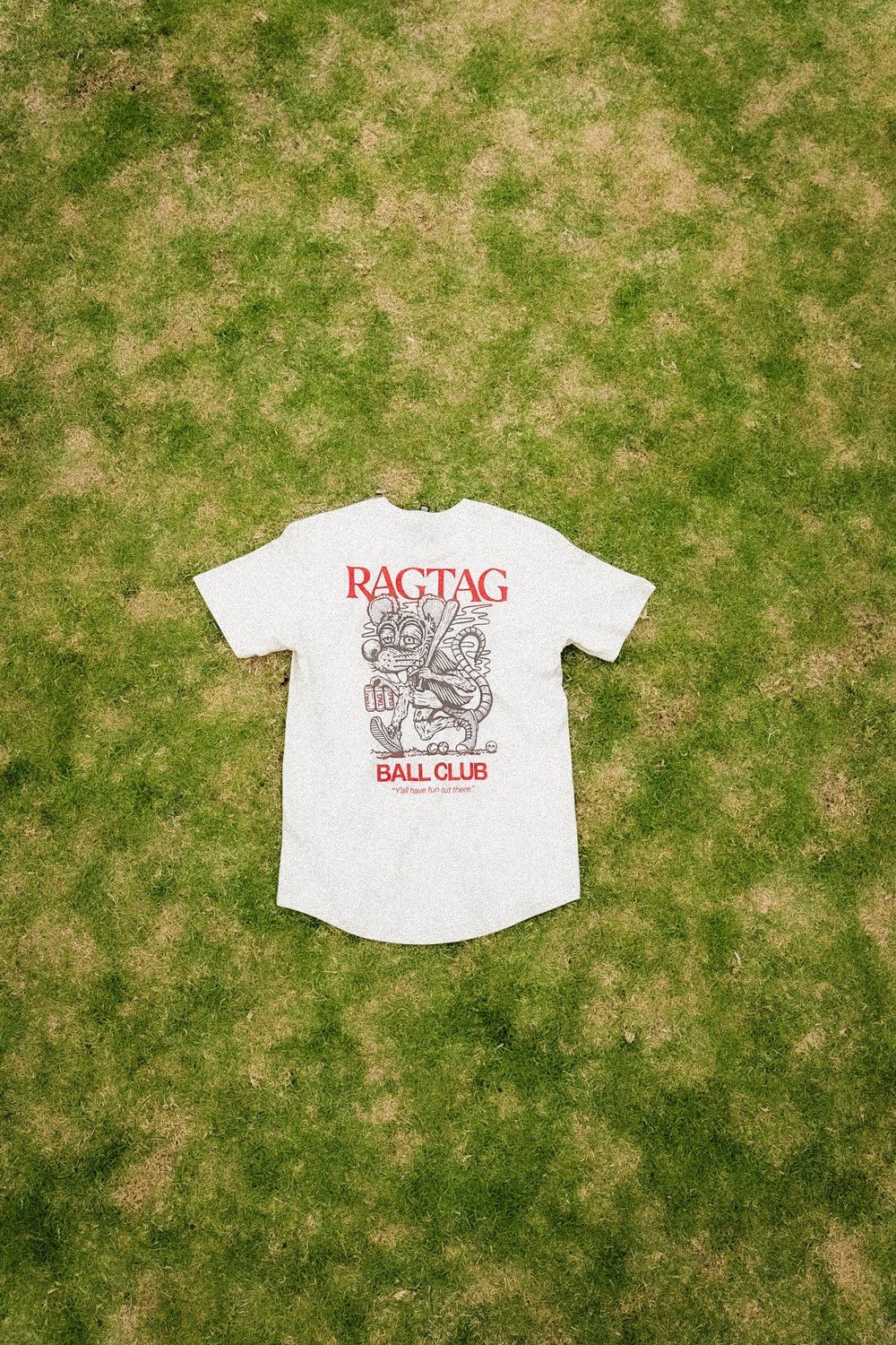 Cream Ragtag graphic tee laid flat on grass
