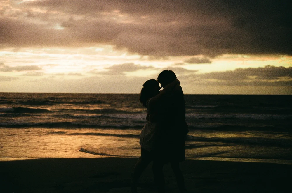 Rose and Brady in silhouette against the sunset over the ocean at La Jolla Shores, shot on 35mm film
