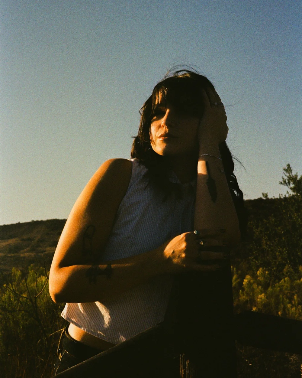 Laurel with a hand in her hair against the hills in El Cajon, shot on 35mm film