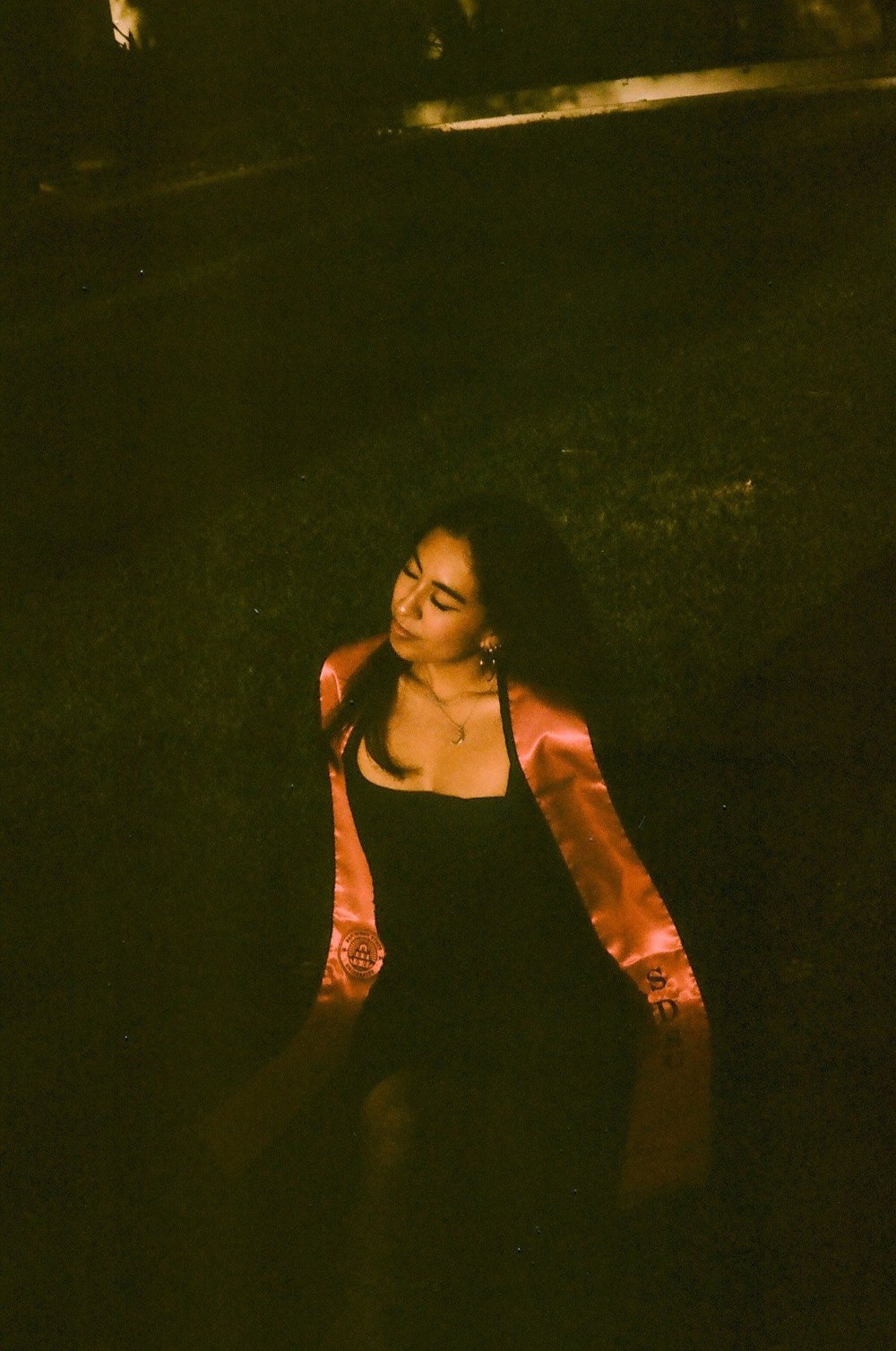 Magaly looking over her shoulder in a dark garden at SDSU, shot on 35mm film