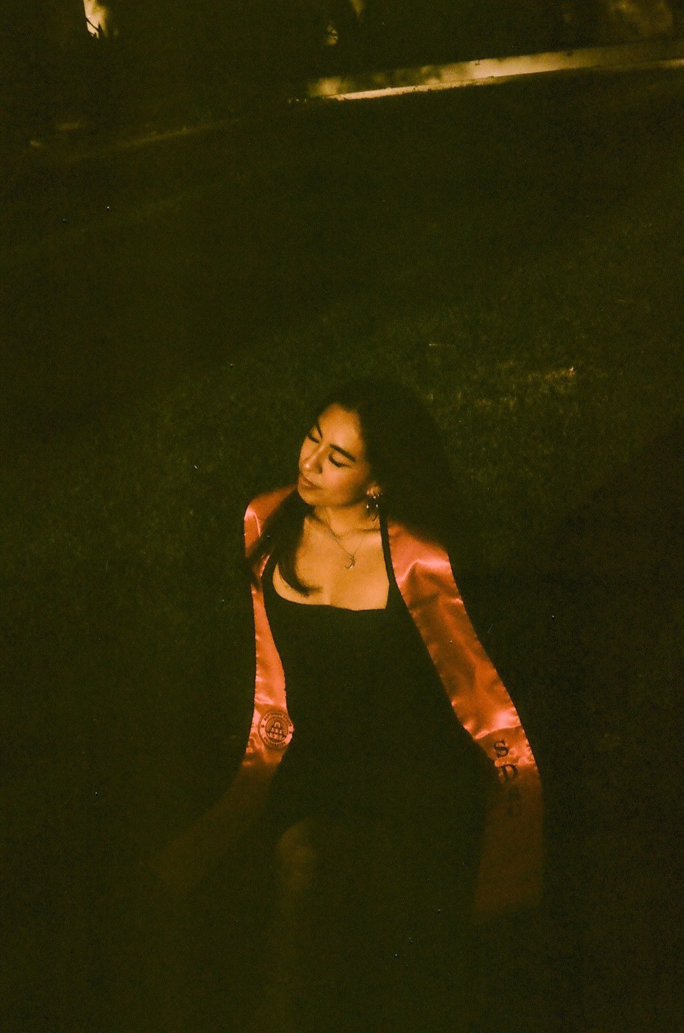 Magaly looking over her shoulder in a dark garden at SDSU, shot on 35mm film