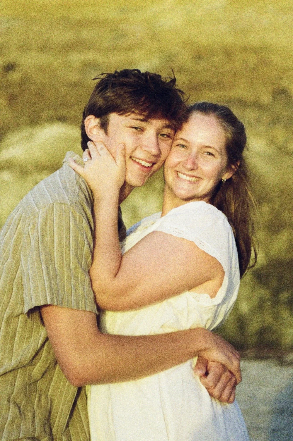 Rose and Brady hugging cheek to cheek and smiling at La Jolla Shores, shot on 35mm film