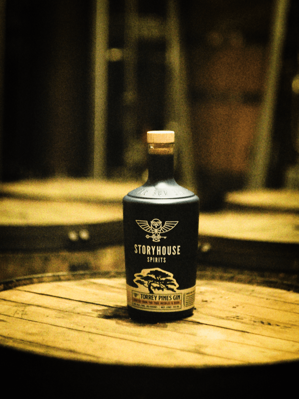 A Storyhouse bottle on a barrel with more barrels behind, shot on film
