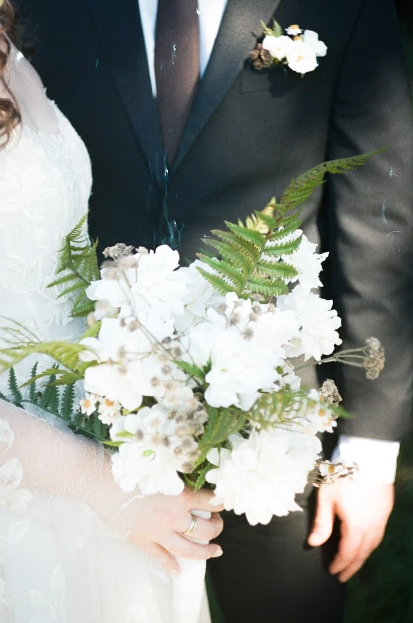 Close-up of Carley's white bouquet held between her and Preston, shot on film