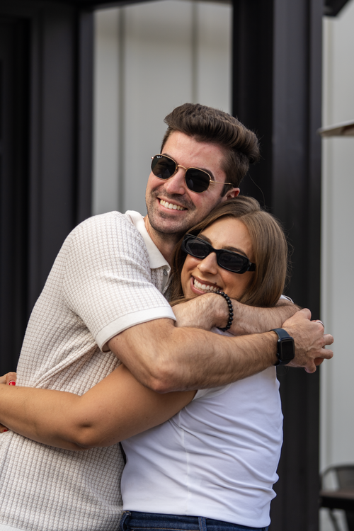 Two guests hugging hello at a Compass Real Estate evening