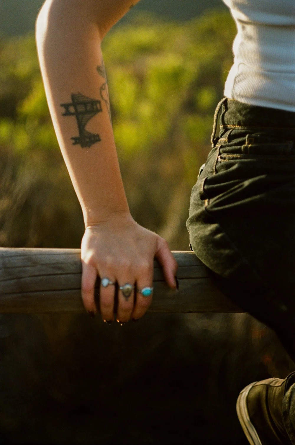 Close-up of Laurel’s hand and tattoos on a wooden fence in El Cajon, shot on 35mm film