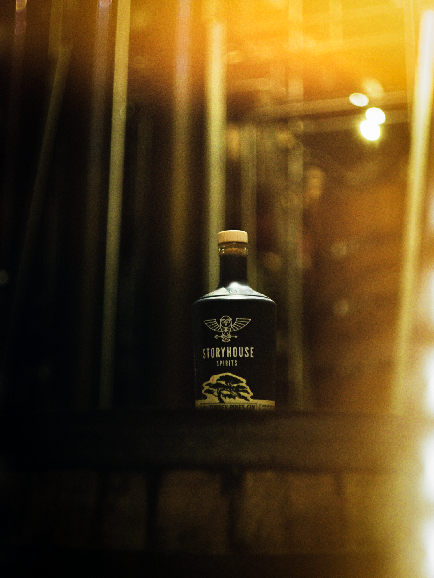 A Storyhouse bottle backlit by warm light through the doors, shot on film