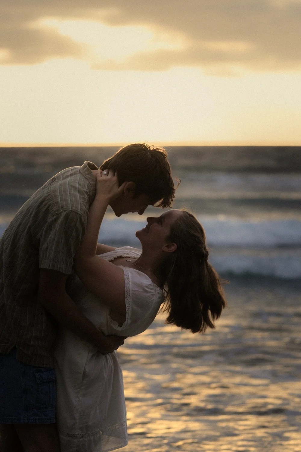 Rose and Brady about to kiss with the ocean behind them at sunset at La Jolla Shores