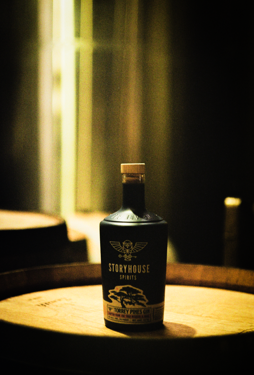 A Storyhouse bottle in a pool of light on a barrel, shot on film