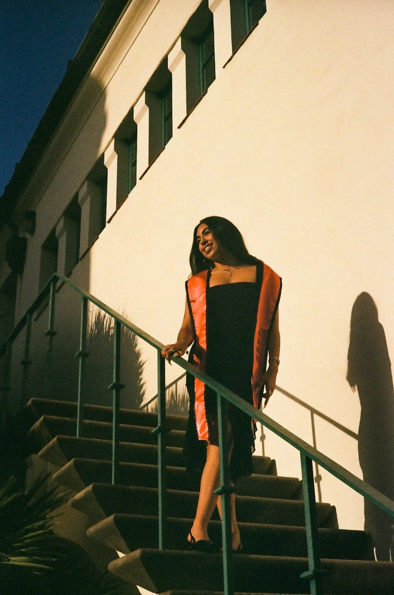Magaly smiling on the staircase in her red stole, shot on film