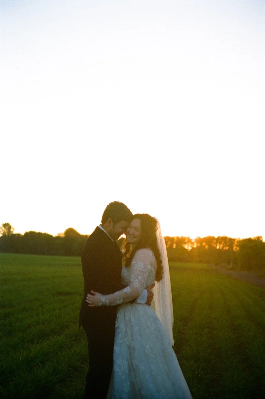 Carley and Preston holding each other in the field at sunset, shot on film