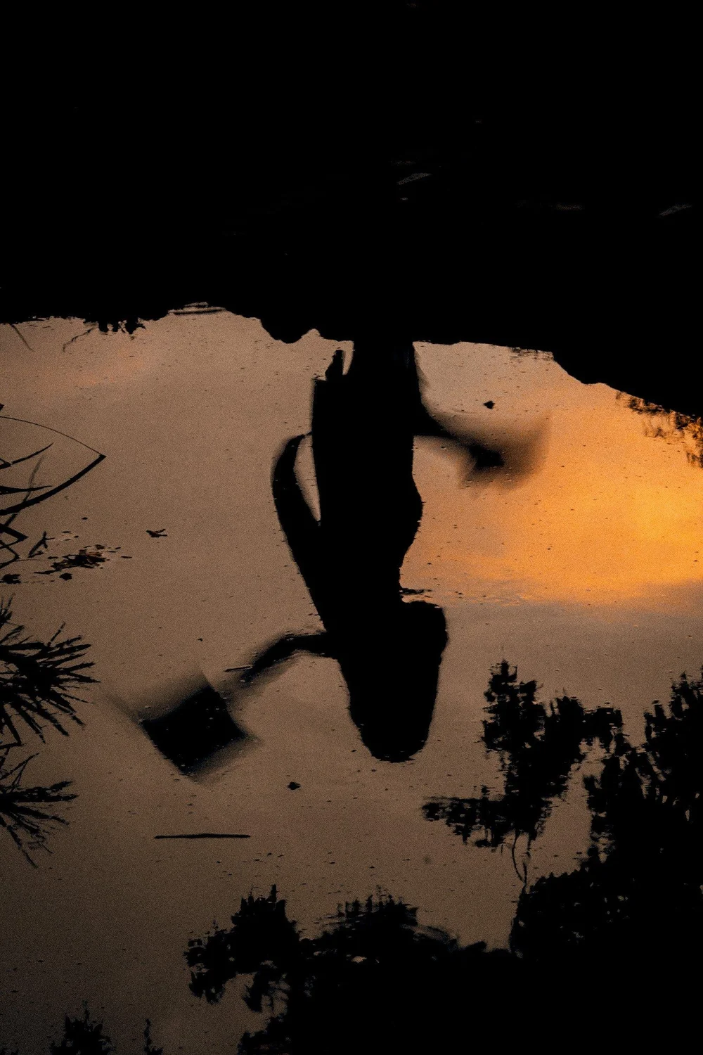 Magaly’s reflection in the water with the sunset behind her