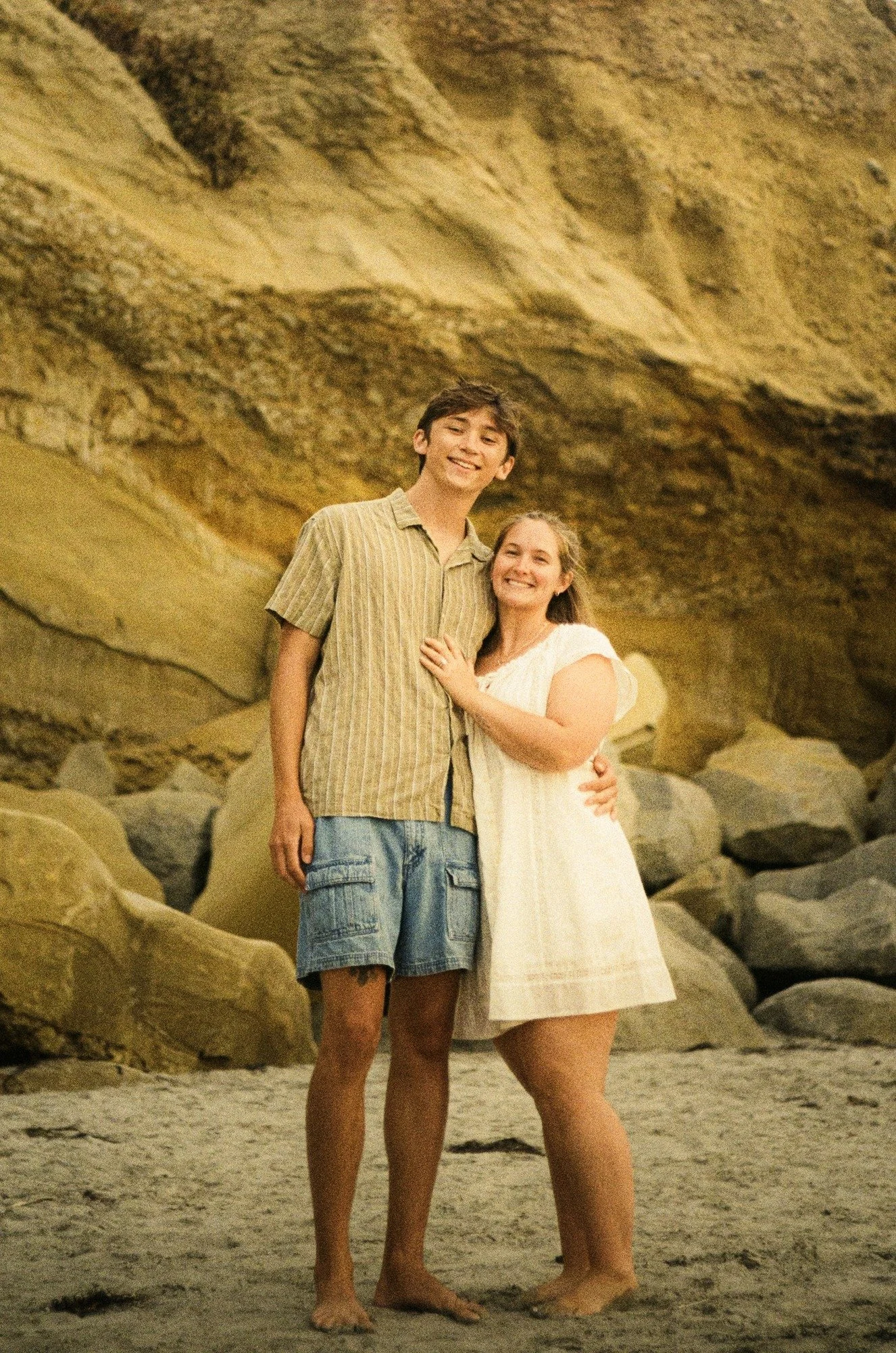 Rose and Brady standing together in front of a sandstone cliff, shot on film