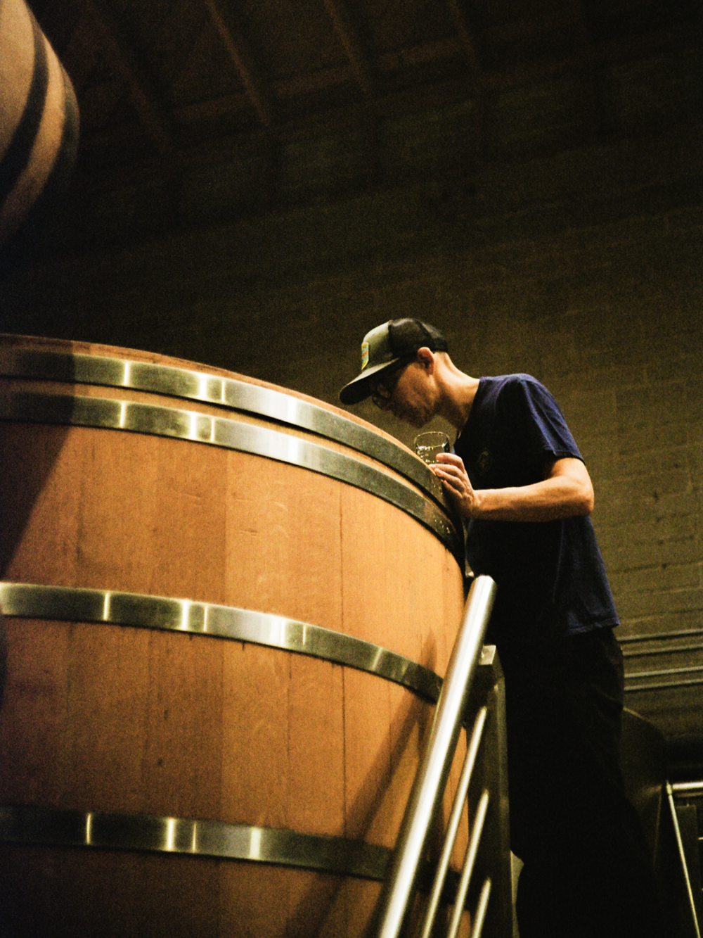 A distiller leaning over a barrel, shot on film