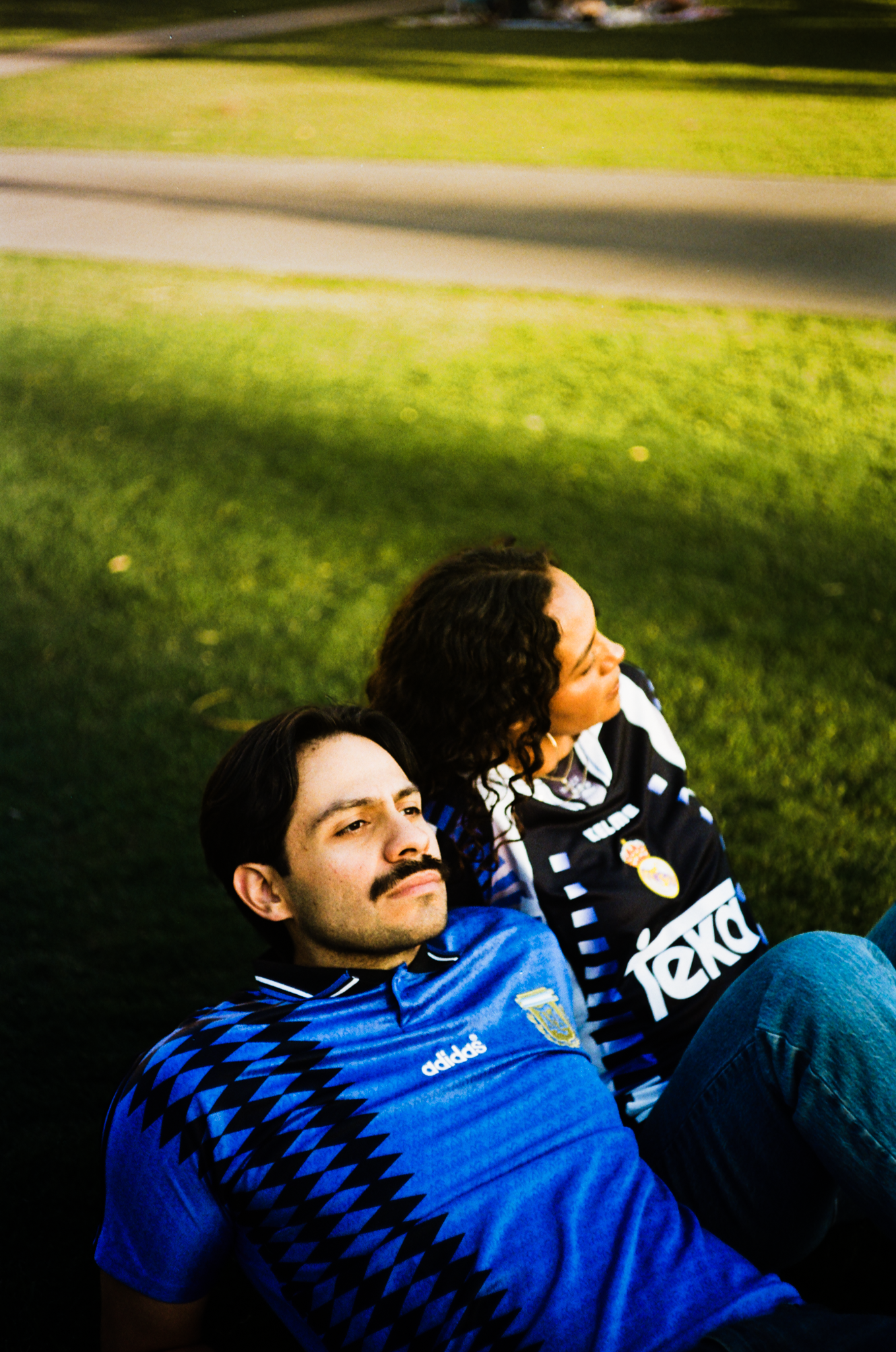 Jackie and Albert lying back on the grass in vintage kits, shot on film