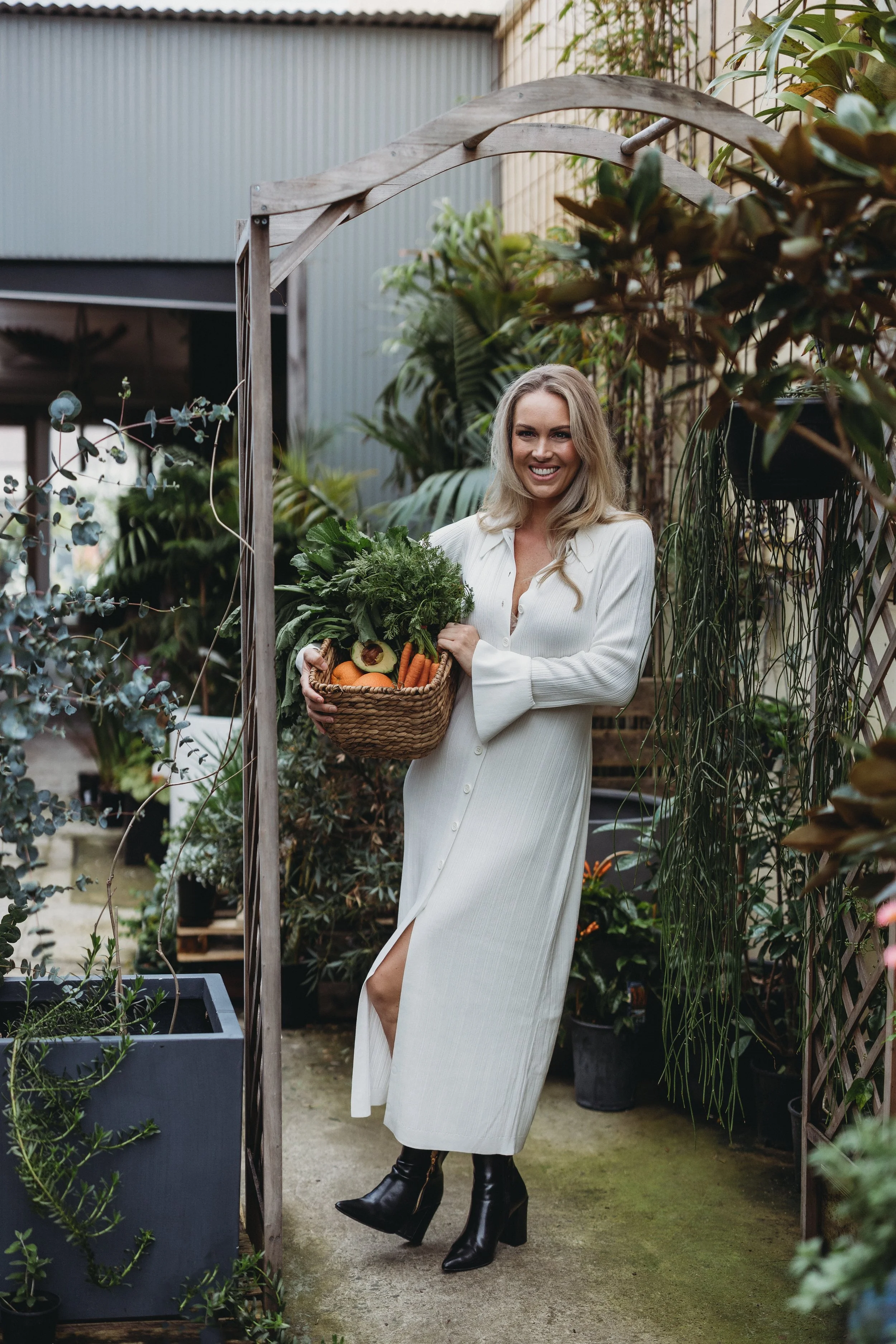 A woman smiling and holding a basket of fresh food