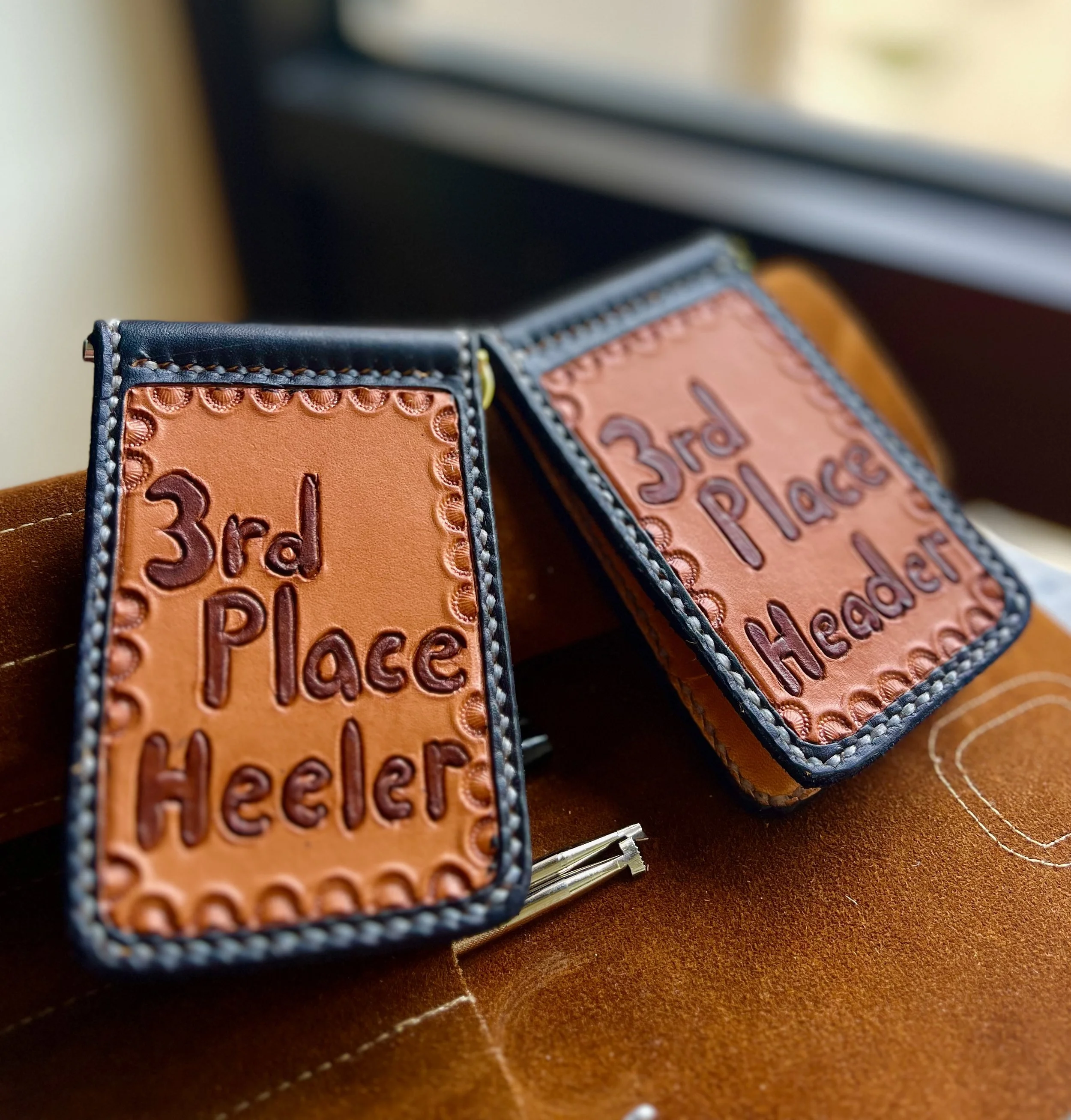 Close-up of leather wallet with embossed text, placed on brown leather surface.