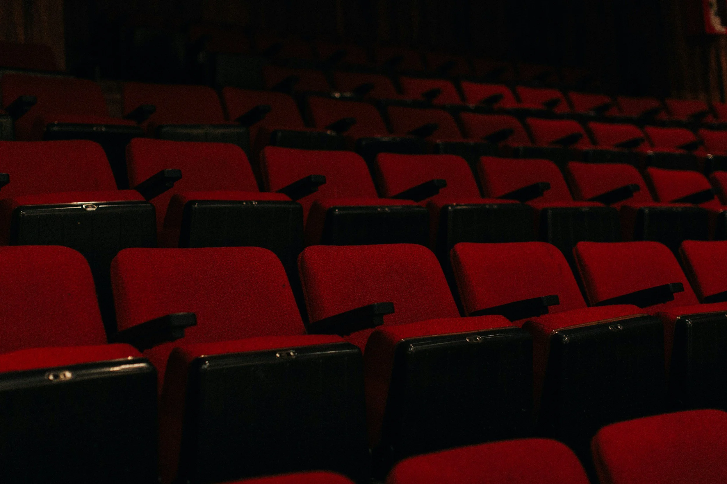 Row of empty red theater seats in a dark auditorium