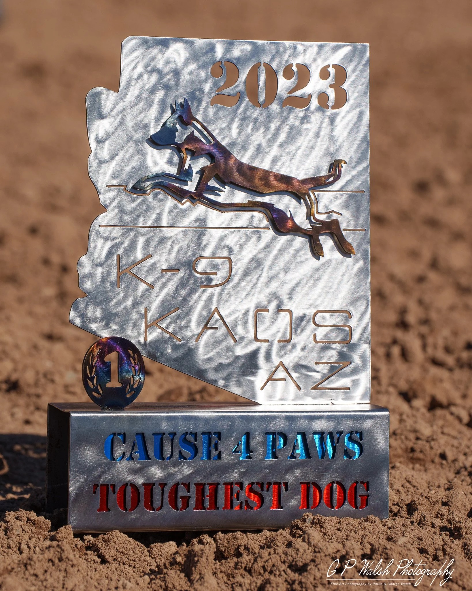 Metal memorial with the year 2023 cut into the top, featuring a stylized dog outline, and engraved text providing a guide for dog behavior with phrases like 'Callie 4 Paws' and 'Touchest Dog'.