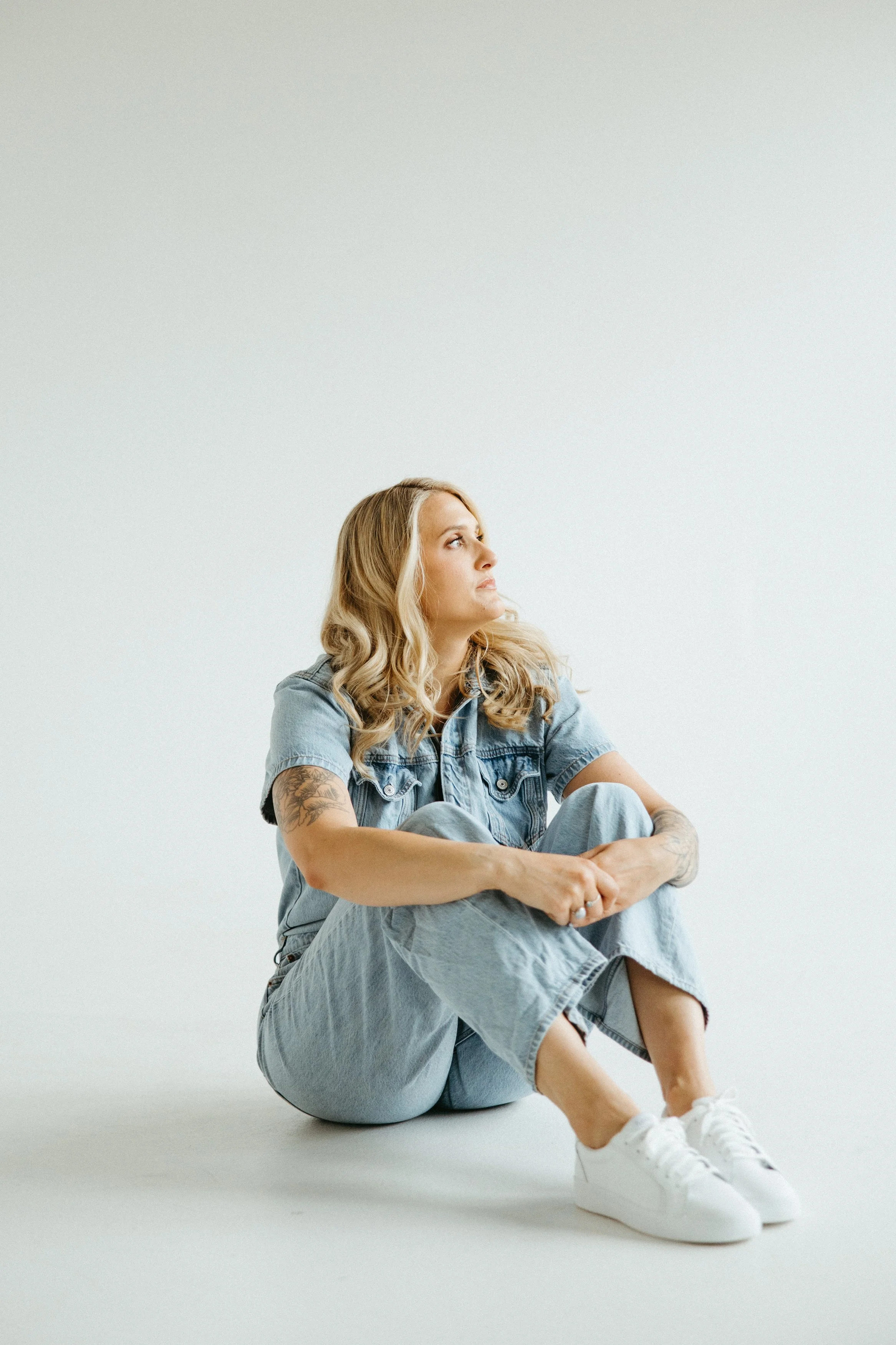 Hannah Guy of Revive Therapy Services sitting reflectively with her knees drawn to her chest, representing the anxiety, overthinking, and emotional overwhelm often experienced with high functioning anxiety.