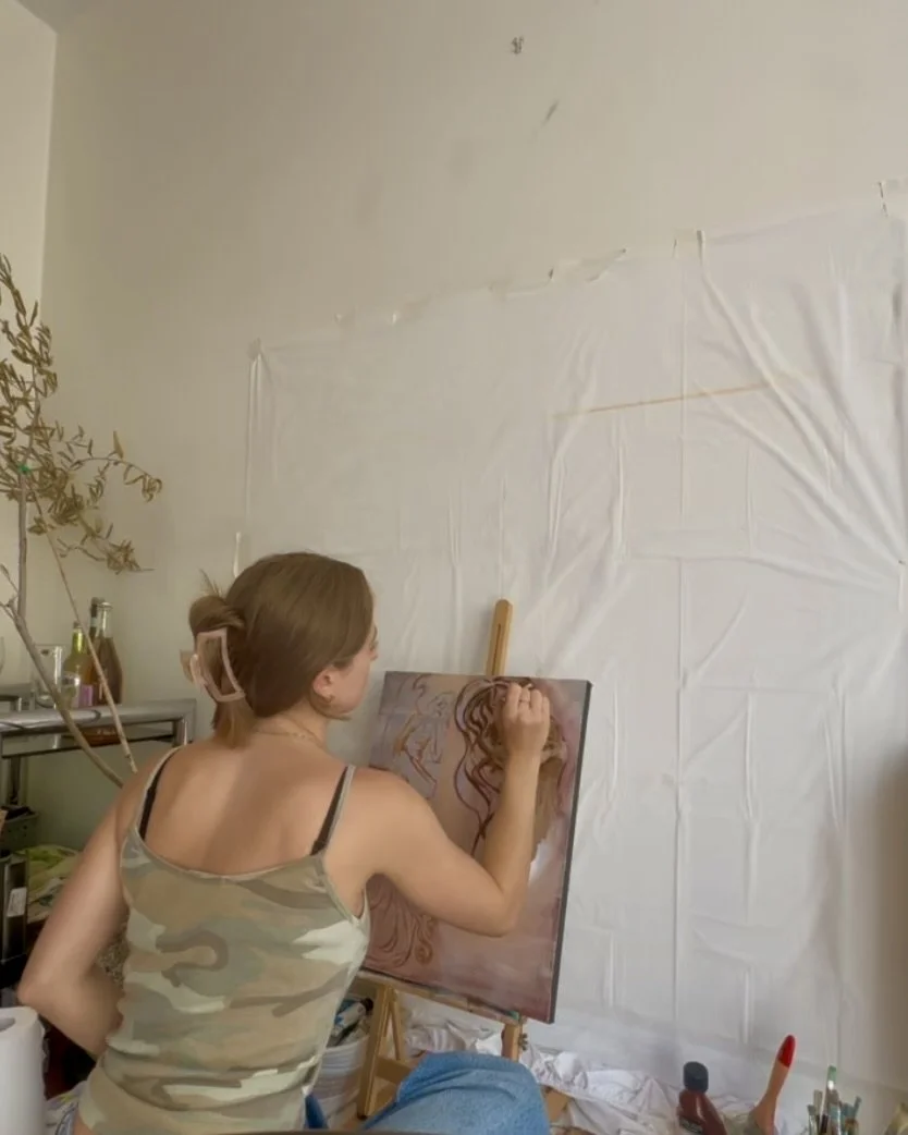 Samara, painting a portrait of a woman with curly hair on a canvas in a room with a white wall.
