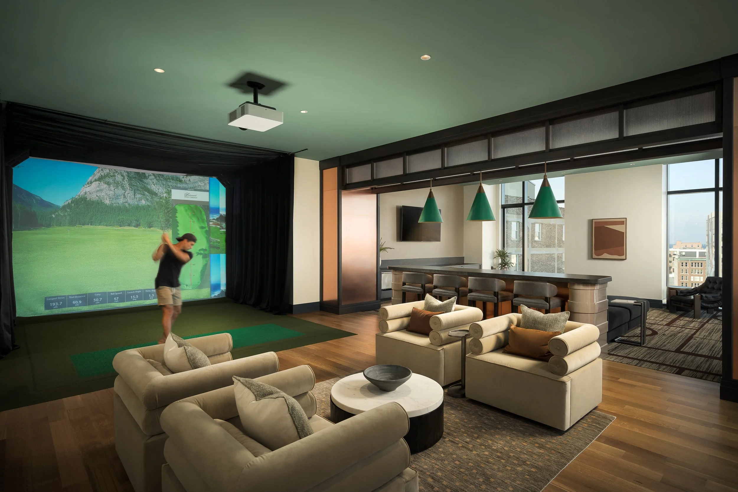 Golf simulator lounge with private screen and casual upholstered seating — luxury apartment amenity interior photography, Milwaukee WI