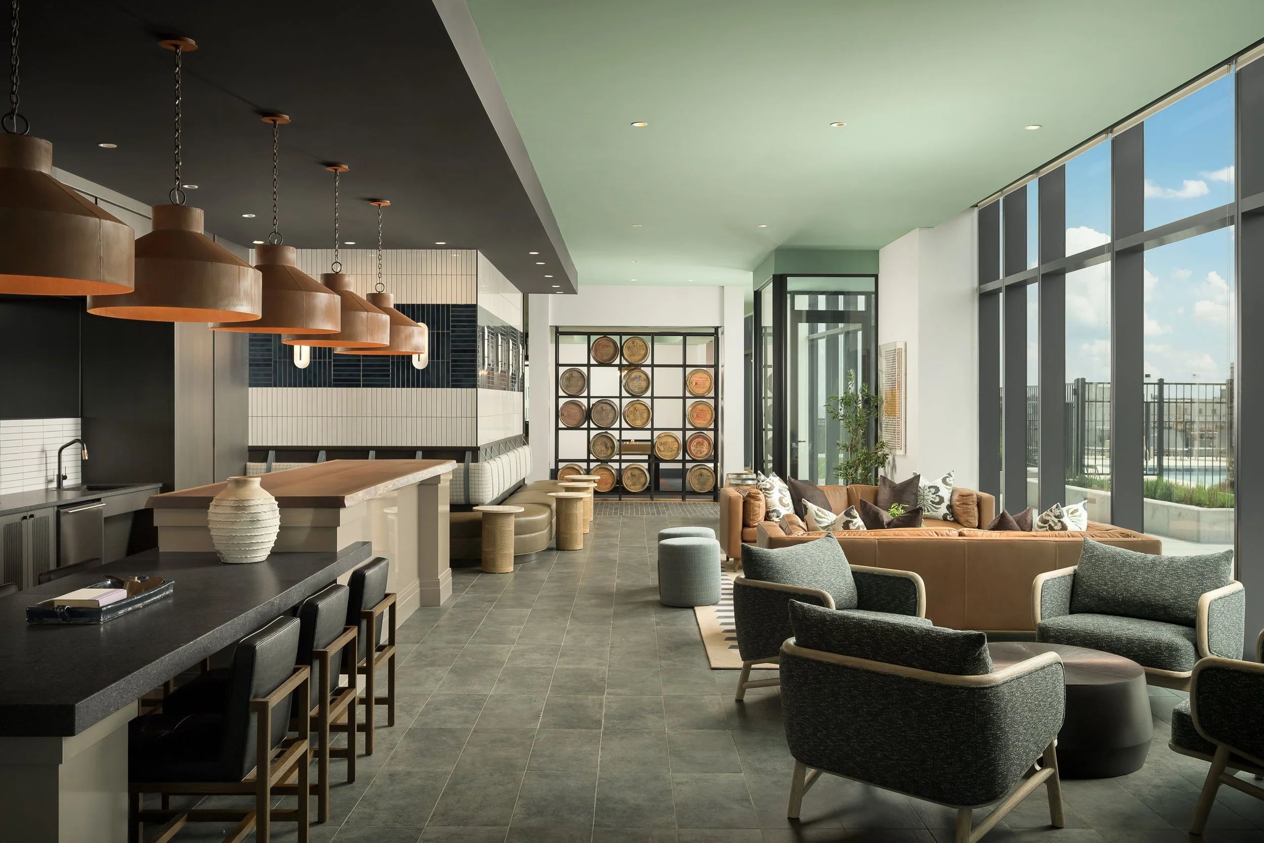 Modern coworking lounge with copper pendants and bar seating overlooking natural light — luxury apartment amenity photography, Milwaukee WI