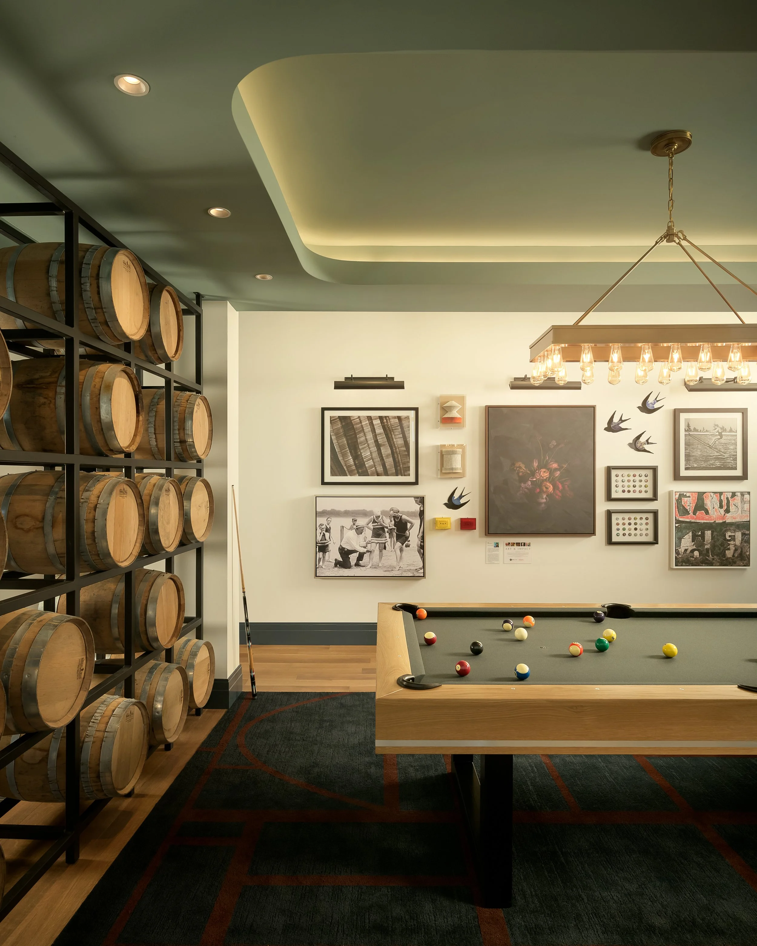 Game room with billiards table, wine barrel wall display, and curated art gallery — luxury residential amenity photography, 333 Water Milwaukee WI