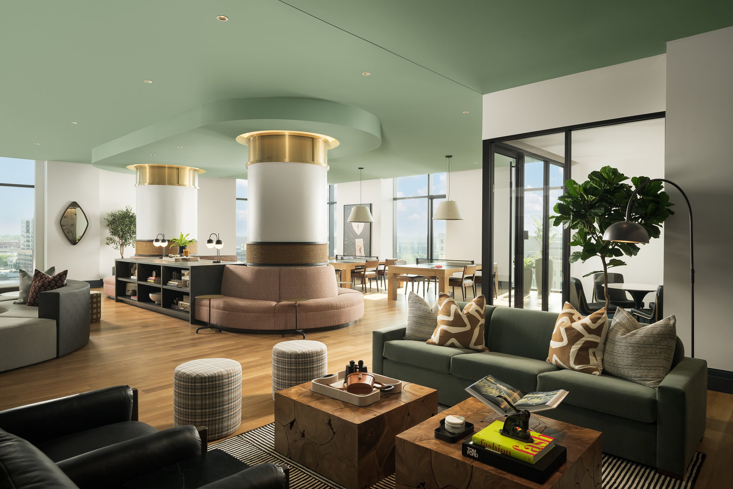 Bright amenity lounge with cylindrical column, contemporary grey seating and abundant natural light — luxury apartment interior design, 333 Water Milwaukee WI