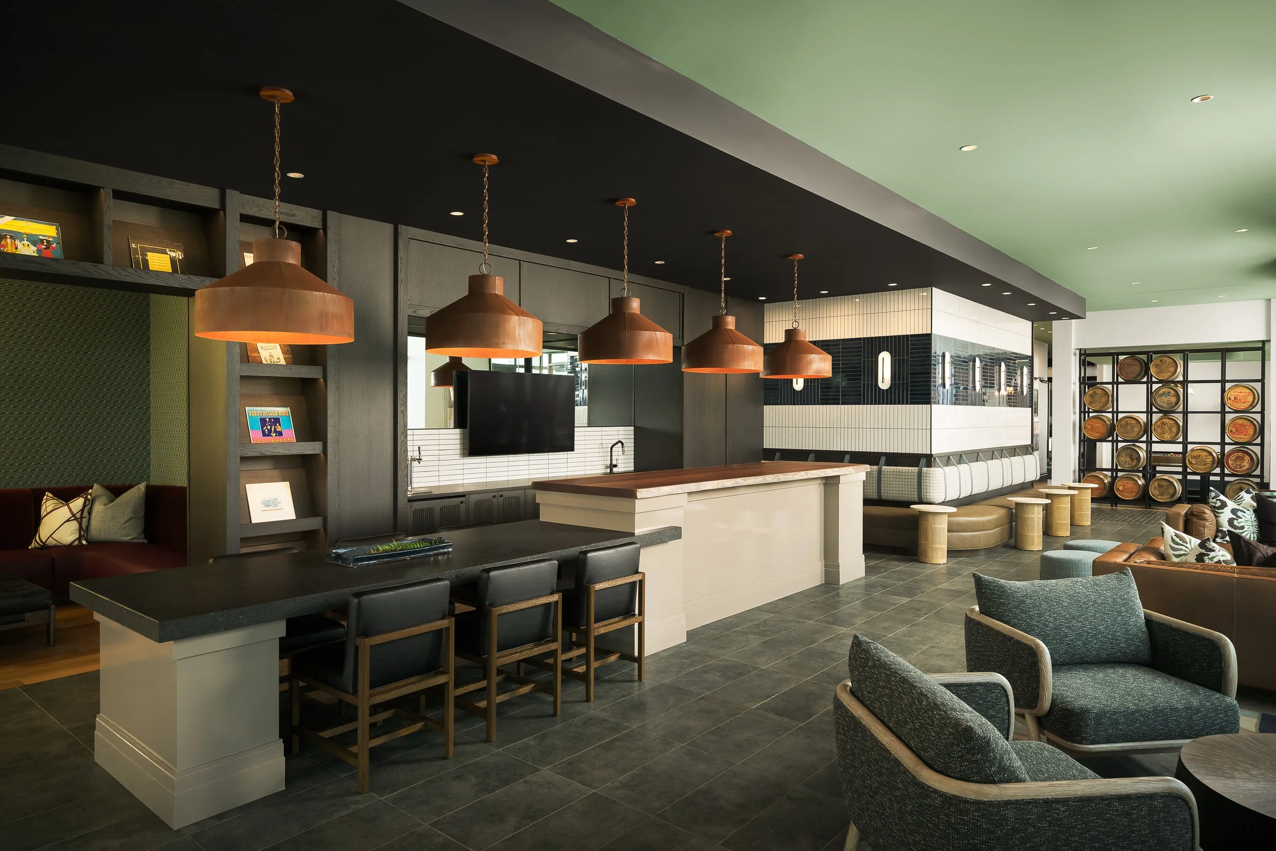 Resident sports lounge and bar with copper pendant lights and dark granite finishes — luxury apartment amenity design, 333 Water Milwaukee WI