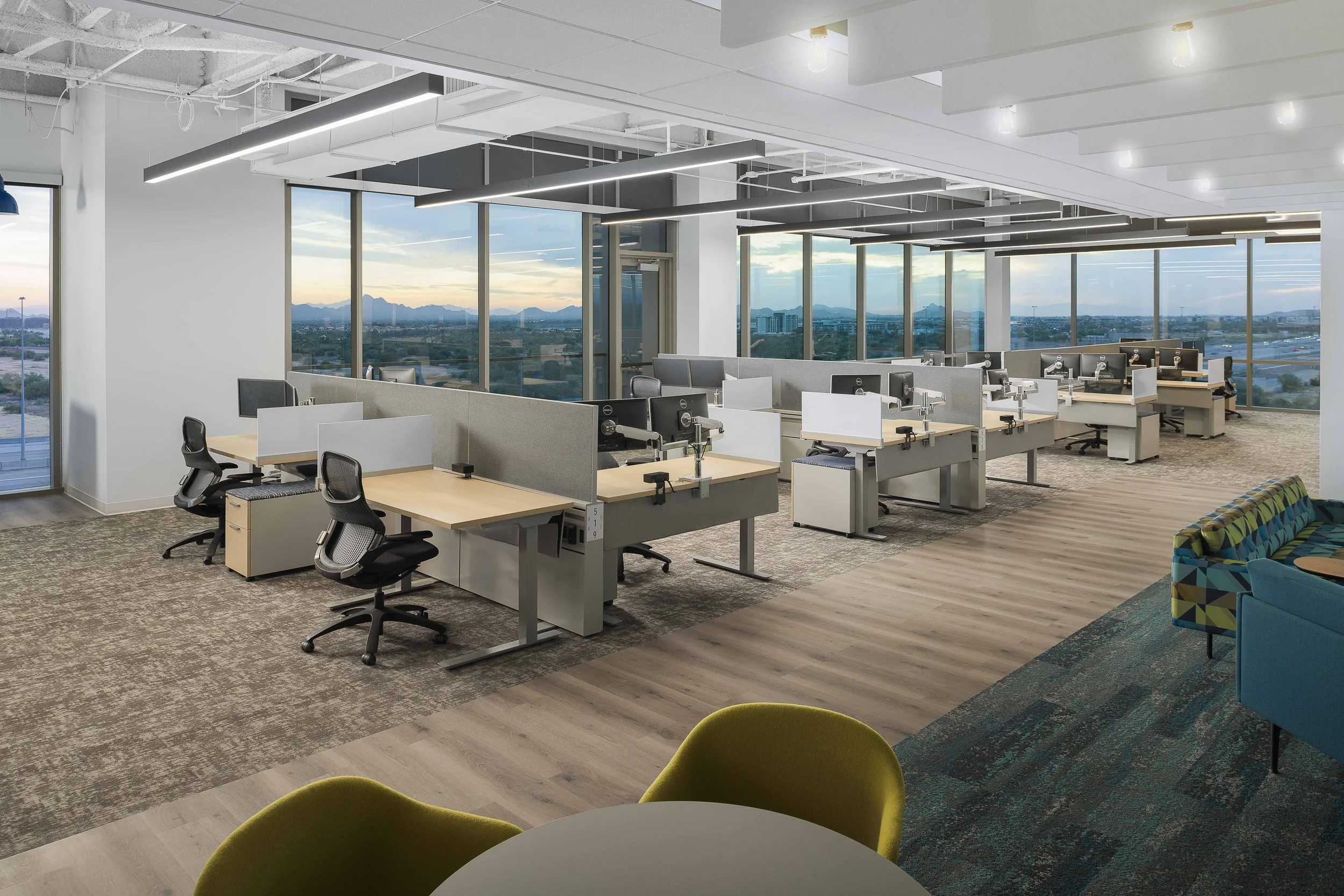 High-rise corner office with open workstations, desert landscape, and McDowell Mountains visible through full-glass walls — Choice Hotels HQ, Cavasson Scottsdale AZ