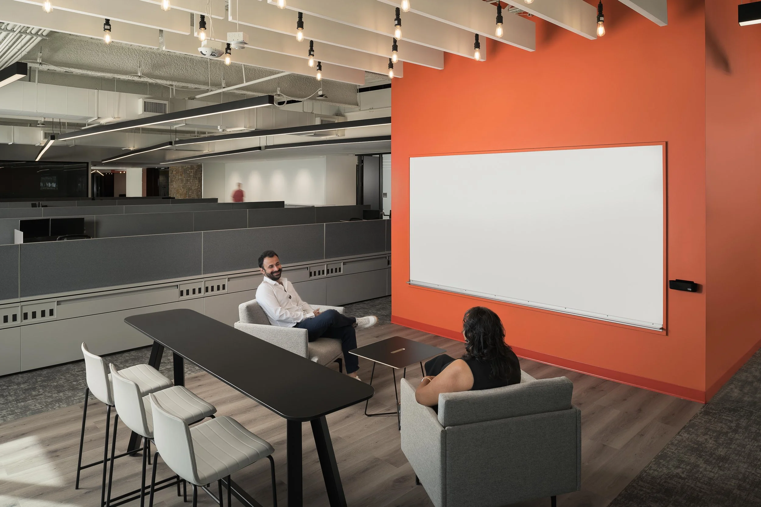 Training room with orange accent wall, whiteboard screen, and bar-height workshop seating — corporate interior photography, Choice Hotels Technology HQ Scottsdale AZ