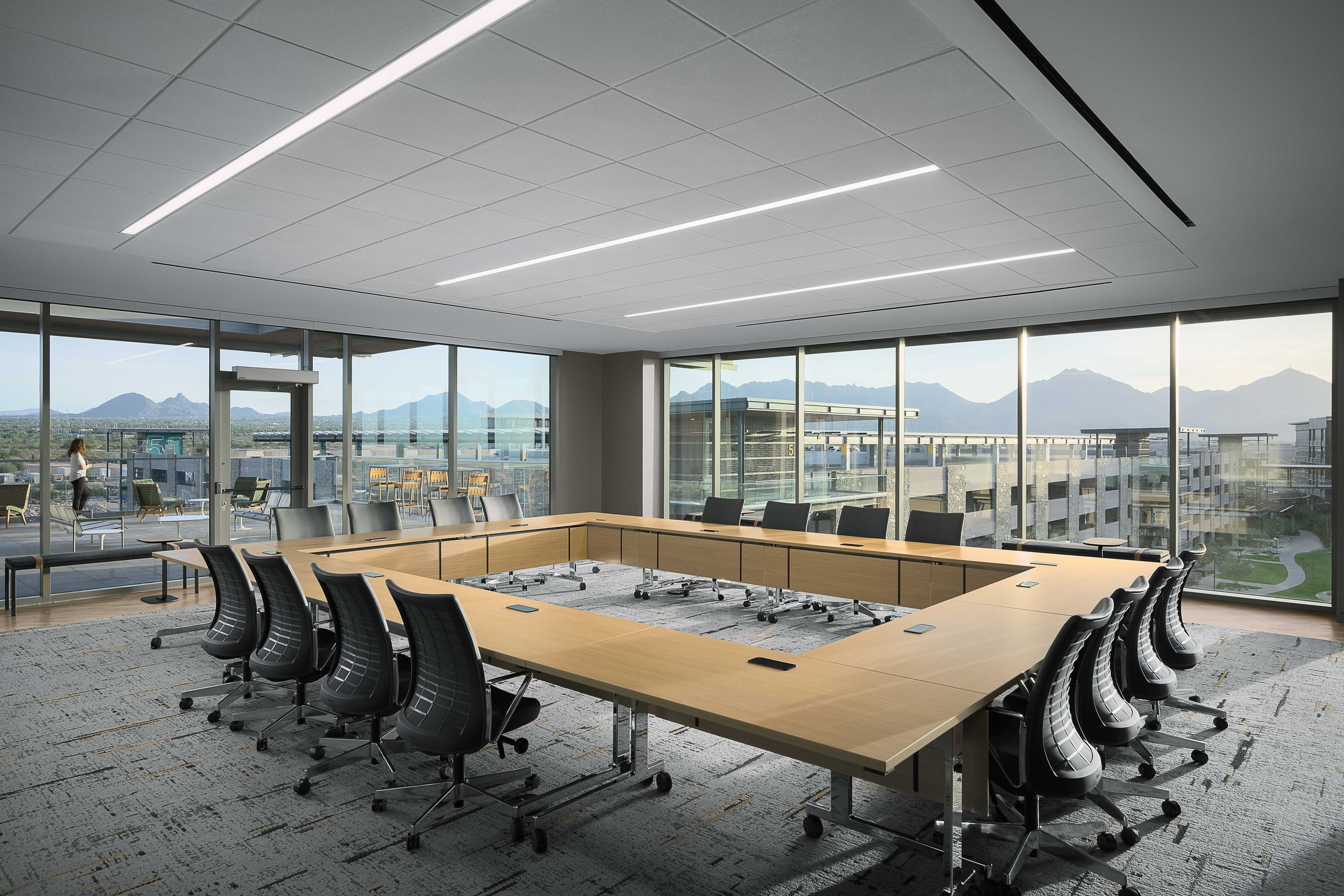 Corner boardroom with long conference table, ergonomic chairs, and McDowell Mountain views through floor-to-ceiling glass — Choice Hotels HQ, Cavasson Scottsdale AZ