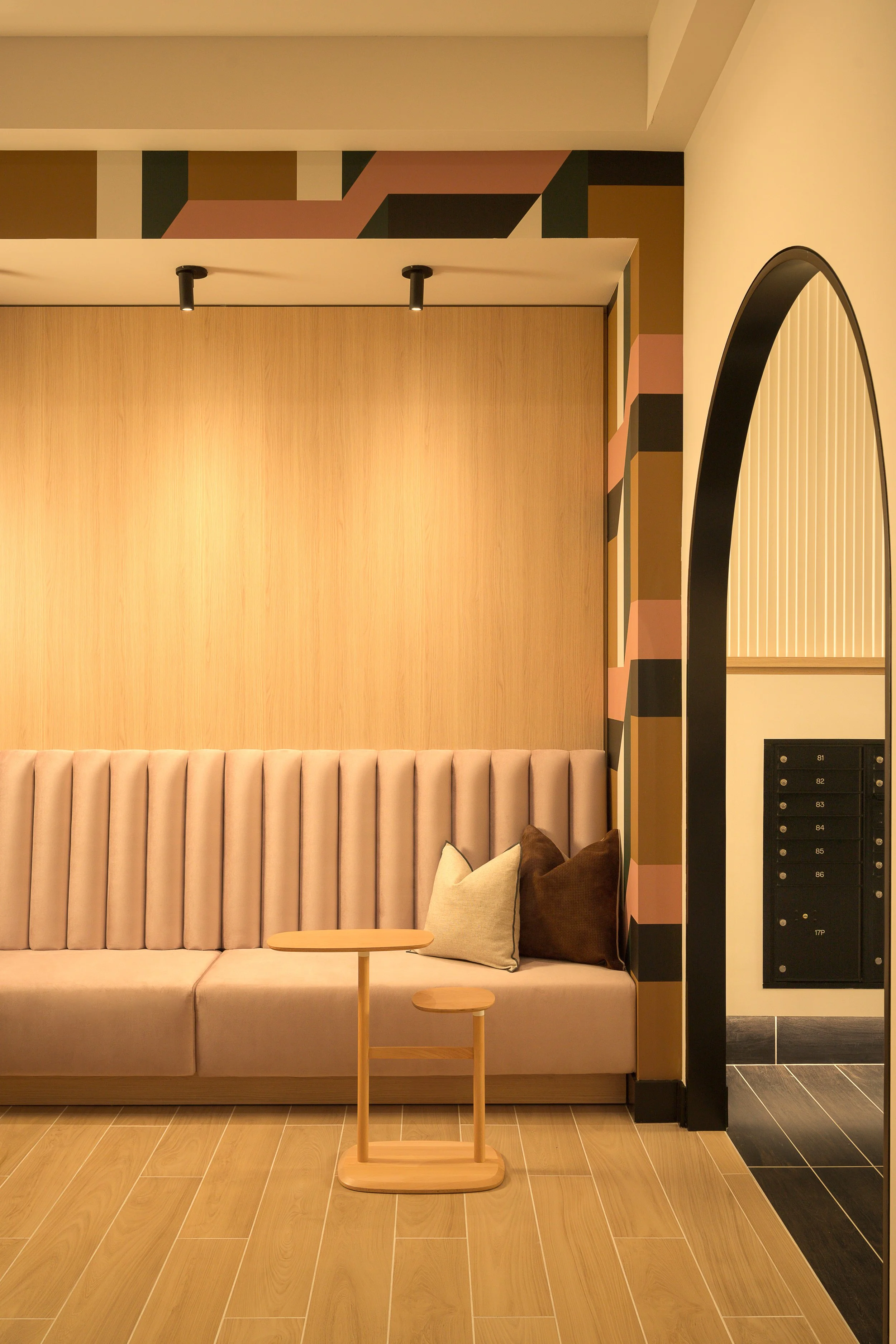 Blush lobby with fluted wall panel, arched mirror, and built-in mailbox feature — boutique apartment interior design photography, Coasterra Fort Lauderdale FL