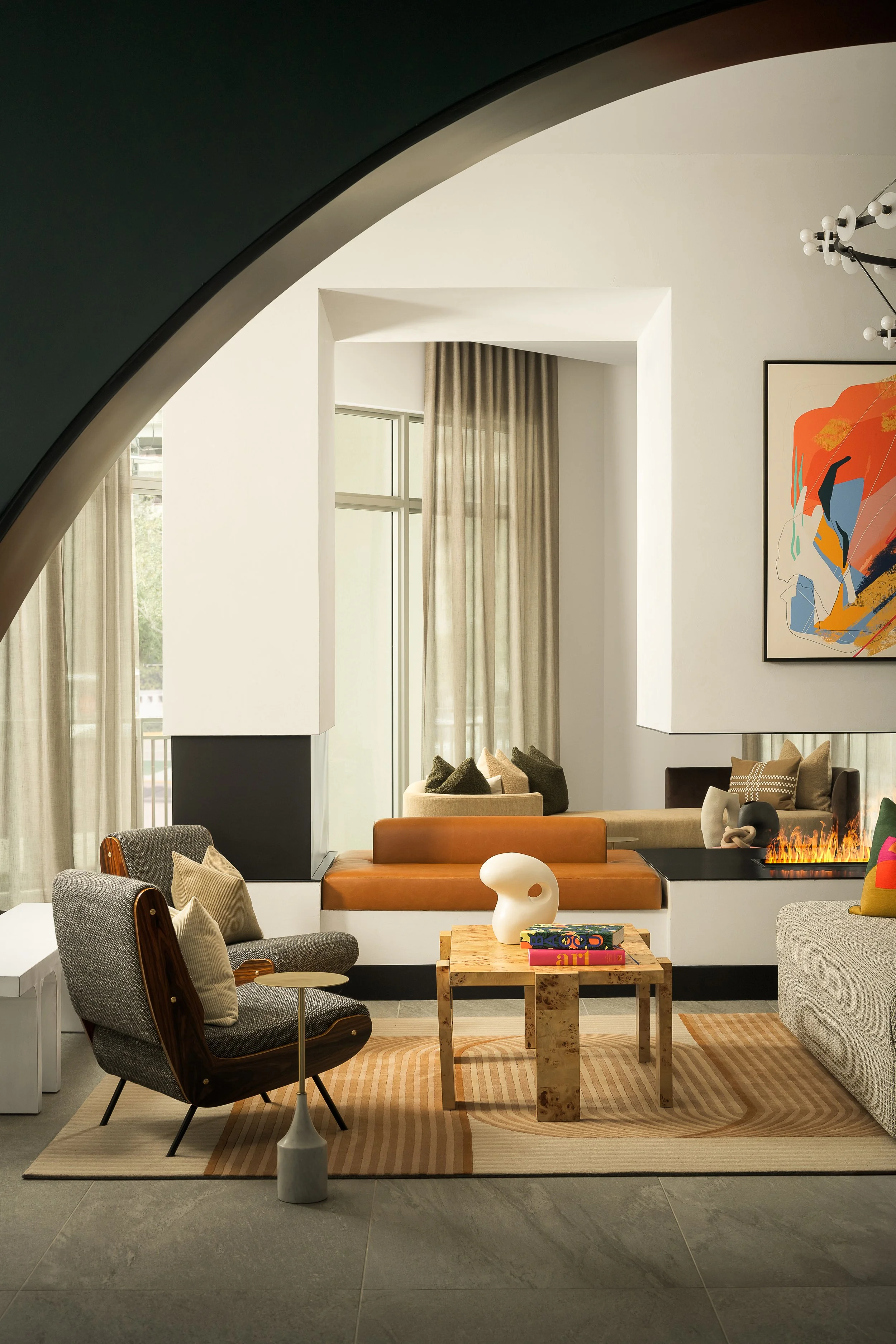 Contemporary lounge with dramatic arched fireplace, colorful abstract art, and curated mid-century furnishings — luxury interior design, Fort Lauderdale FL