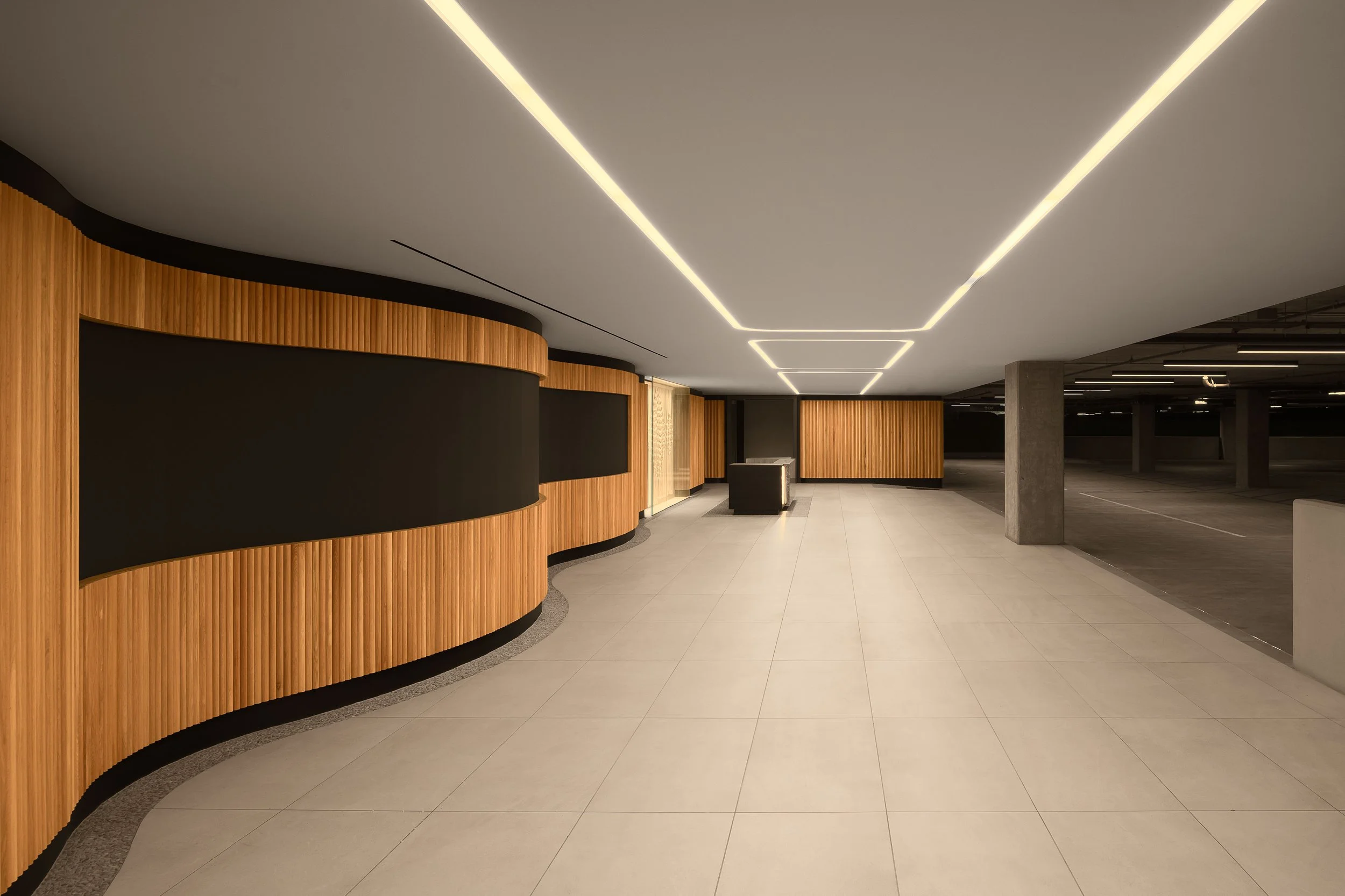 Clean corridor with recessed linear LED lighting and curved wood slat wall paneling — luxury commercial interior architecture, Los Angeles CA