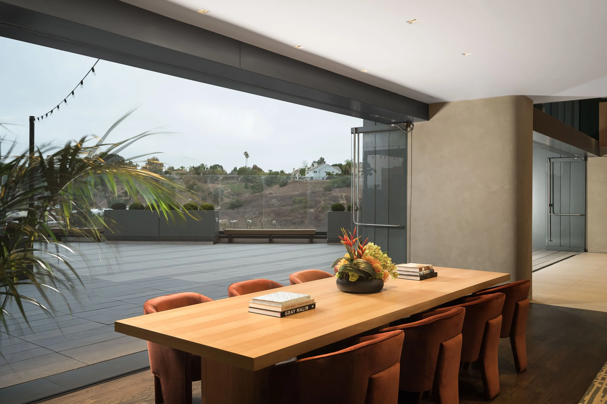 Indoor-outdoor dining room with hillside garden views through open glass panels — luxury commercial architecture photography, Los Angeles CA